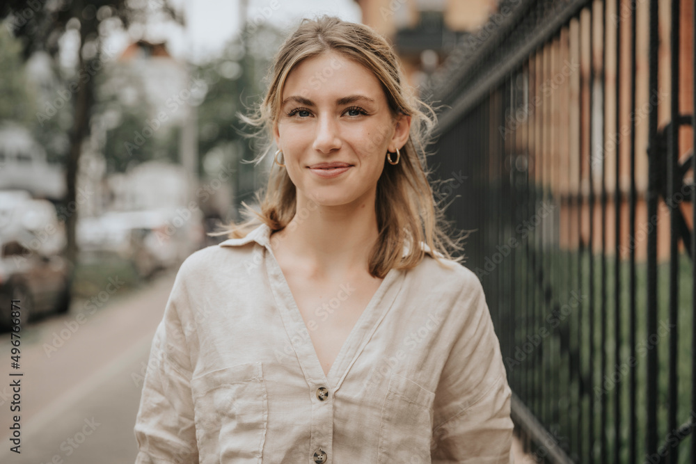 Smiling young woman with blond hair standing on footpath Smiling young woman with blond hair standing on footpath