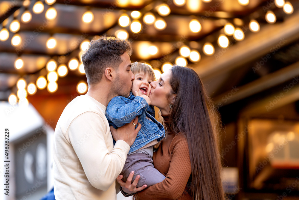 Parents kissing son standing in front of illuminated ceiling Parents kissing son standing in front of illuminated ceiling