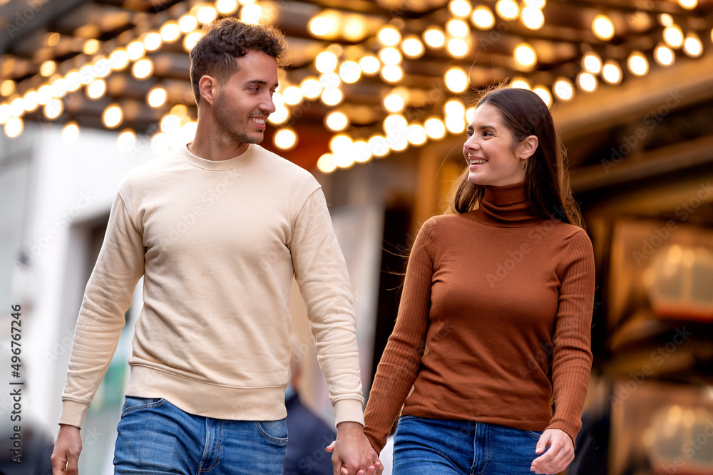 Smiling couple walking with holding hands in front of illuminated ceiling Smiling couple walking with holding hands in front of illuminated ceiling