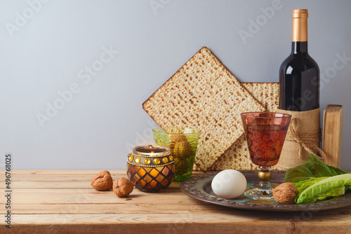 Jewish holiday Passover celebration concept with wine, matzah and seder plate on wooden table over gray background.