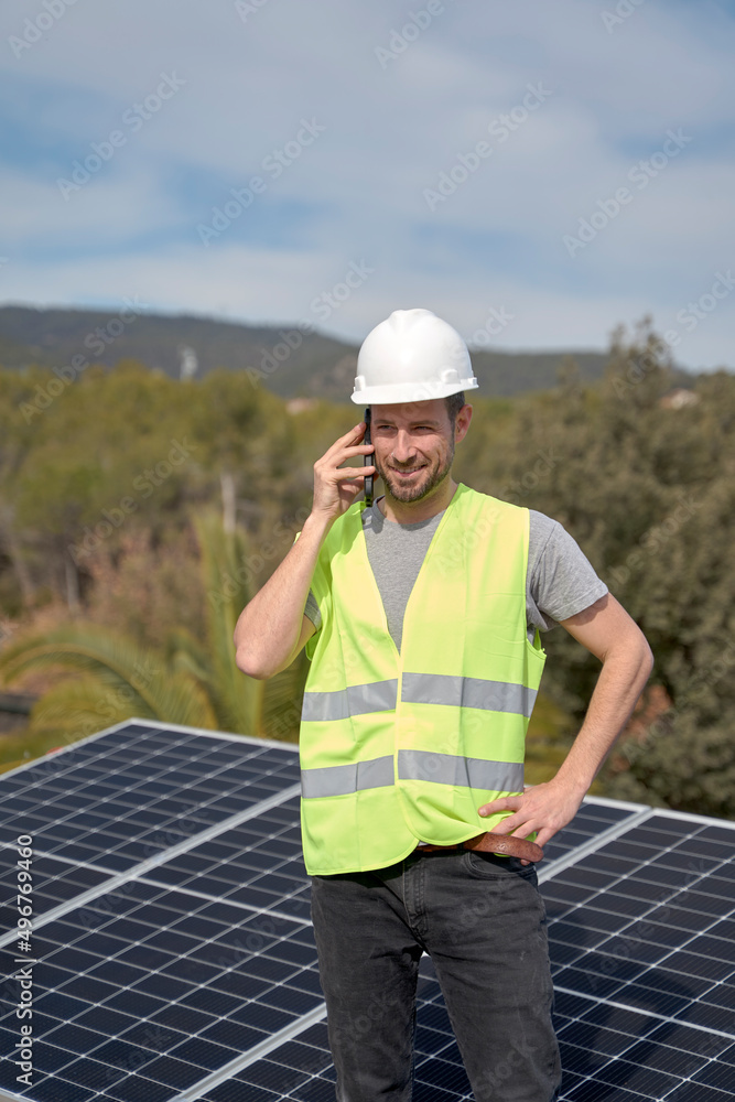 Engineer talking on mobile phone standing in front of solar panels on sunny day Engineer talking on mobile phone standing in front of solar panels on sunny day