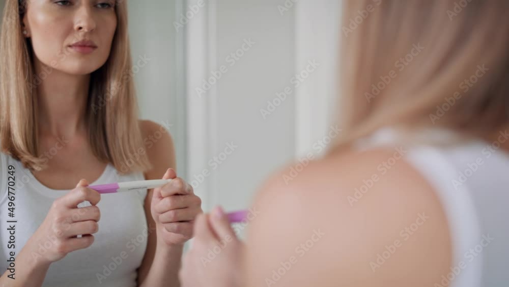 Young woman standing in front of bathroom mirror and waiting for pregnancy test results. Shot with RED helium camera in 8K. Young woman standing in front of bathroom mirror and waiting for pregnancy test results. Shot with RED helium camera in 8K.