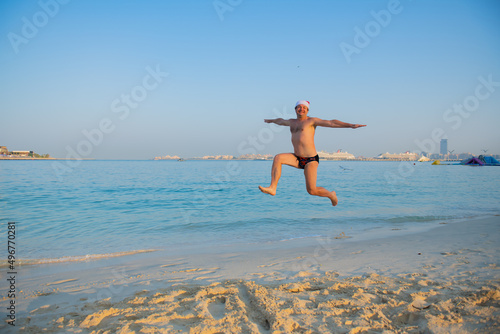 a man jumping on the beach wearing a santa hat