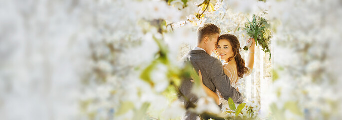 Amazing smiling wedding couple. Pretty bride and stylish groom posing and kisses. Flowery Romantic moment.