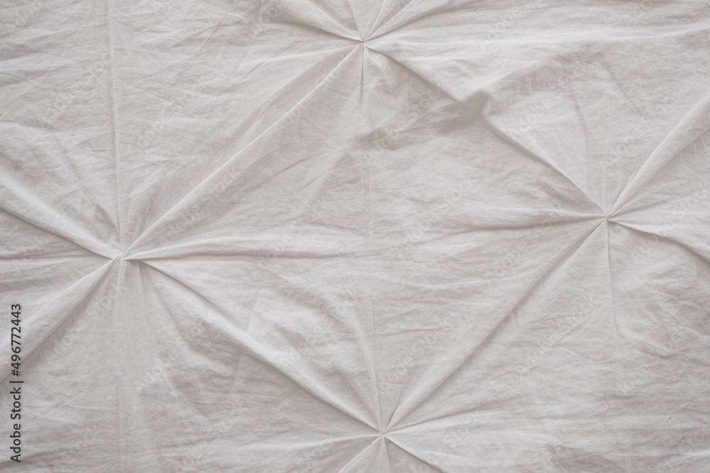 wrinkled white fabric with decorative pinches. bed linen and textiles in the interior. textile surface. copy space.