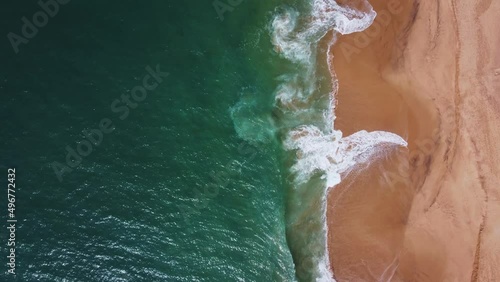 The waves roll on the shore. Yellow sandy beach with blue sea. Aerial top view
