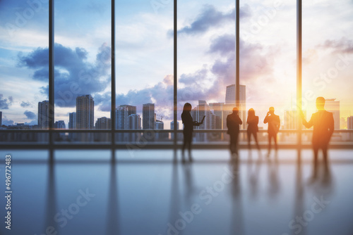 Backlit crowd of businesspeople working together in bright office interior with sunlight and city view with clouds. Teamwork and corporate workplace concept. Double exposure.