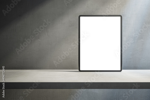 Close up of empty white tablet on desktop and concrete wall background with shadows and mock up place. Device presentation concept. 3D Rendering.