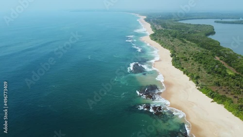 Sea coast, view from the height. Sandy beach with blue sea. A deserted beach with a bird's eye view. Sea waves roll on the sandy beach. Beautiful sea landscape. Ocean, waves, sand.