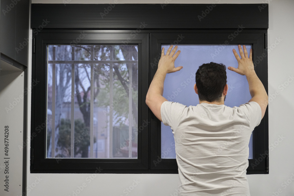 Young latin man installing frosted window vinyl on wet window glass. Young latin man installing frosted window vinyl on wet window glass.