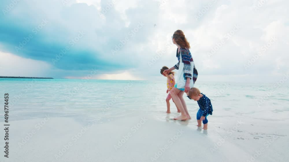 Woman walks with kids on the tropical sandy beach Woman walks with kids on the tropical sandy beach