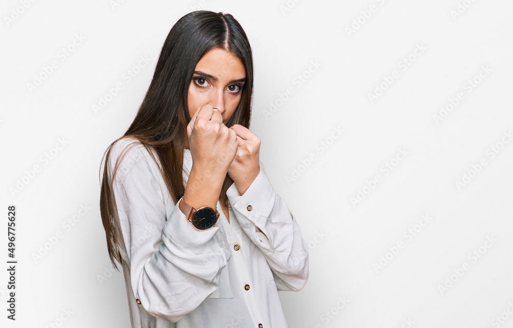 Young beautiful woman wearing casual white shirt ready to fight with fist defense gesture, angry and upset face, afraid of problem Young beautiful woman wearing casual white shirt ready to fight with fist defense gesture, angry and upset face, afraid of problem