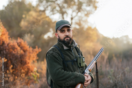 Hunter posing while holding his shotgun and looking at camera