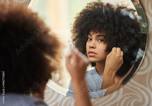 Electric life and soul. Portrait of a beautiful woman looking in the mirror while applying makeup at home.