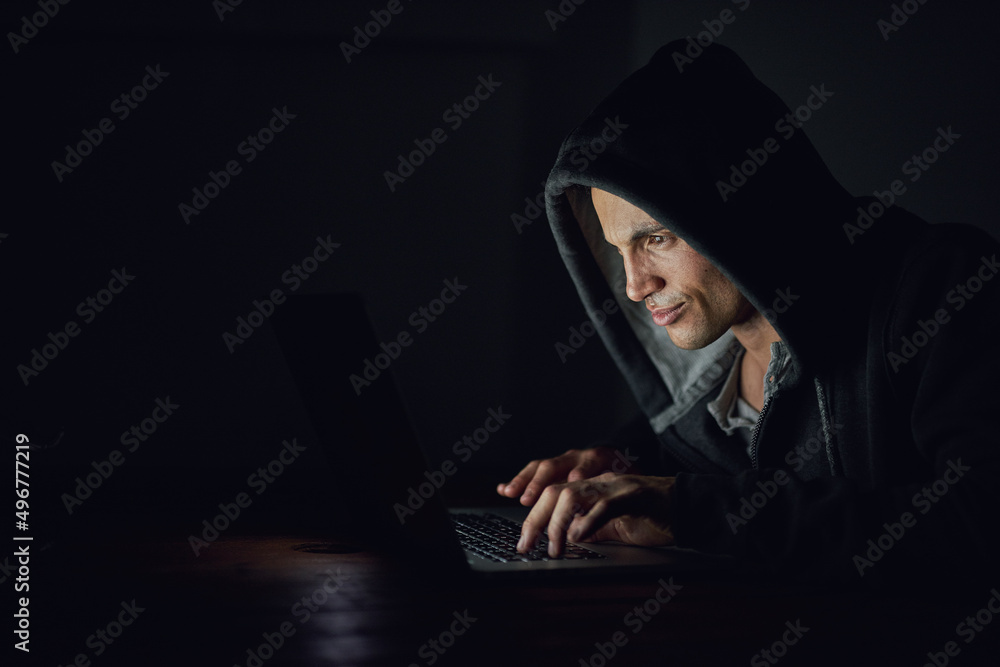 Protect yourself before its too late. Shot of a hooded computer hacker using a laptop in the dark. Protect yourself before its too late. Shot of a hooded computer hacker using a laptop in the dark.
