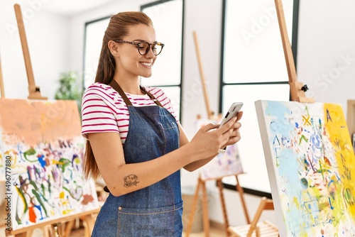 Young woman smiling confident using smartphone at art studio