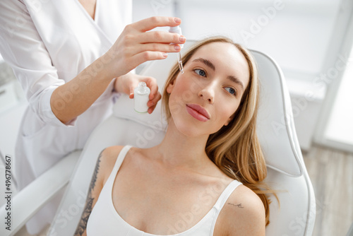 Beautician applying vitamin serum on woman face