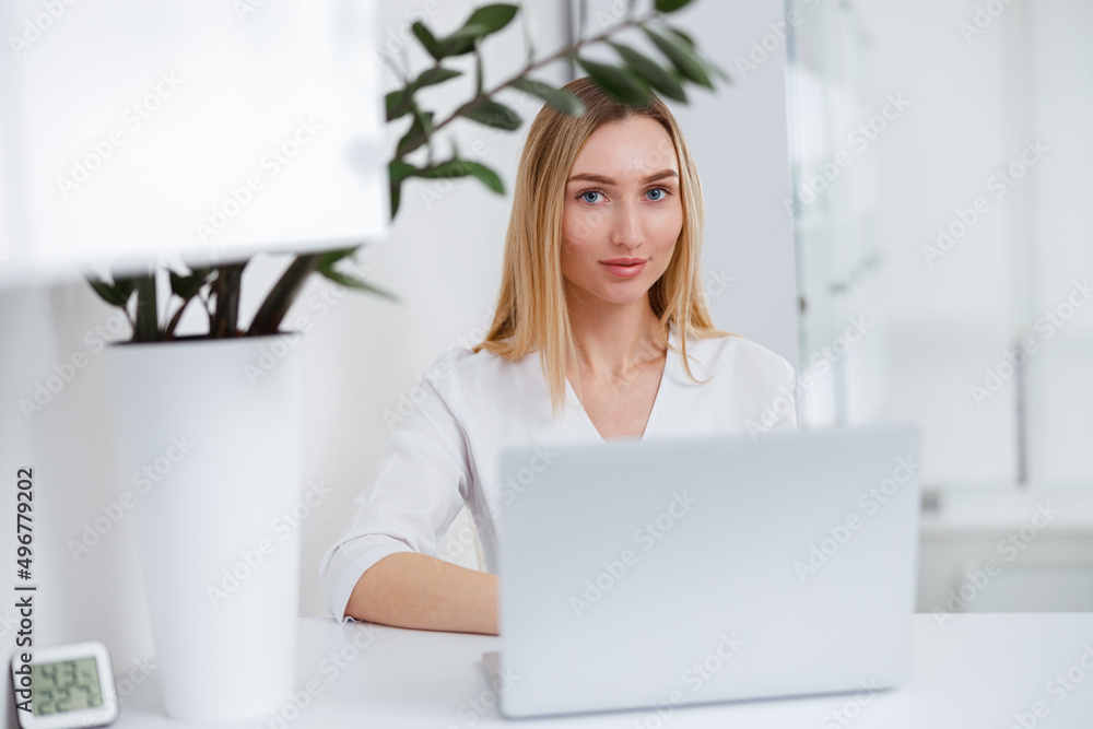 Female doctor cosmetologist using laptop in beauty salon