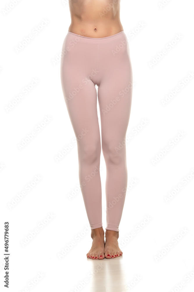 Front view of a female bare legs in sport pink tights on white background Front view of a female bare legs in sport pink tights on white background