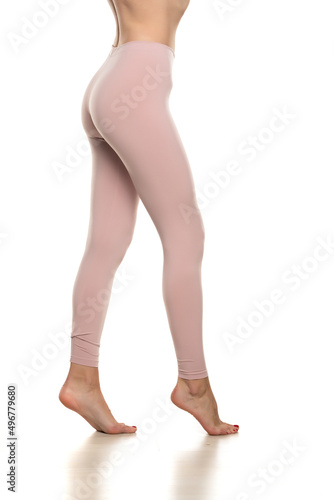 Side view of a female bare legs in sport pink tights on white background