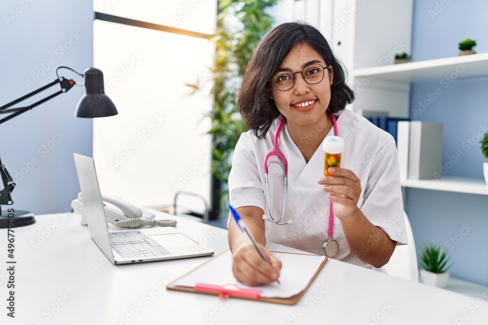 Young latin woman wearing doctor uniform prescribe pills at clinic Young latin woman wearing doctor uniform prescribe pills at clinic