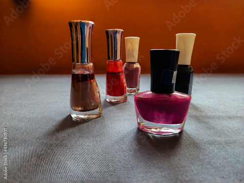 Group of five different nail polish or nail paint color bottles kept on table under natural light. pink, red, black shiny brown, light brown color shades of nail paint. Picture captured at Bangalore. photo