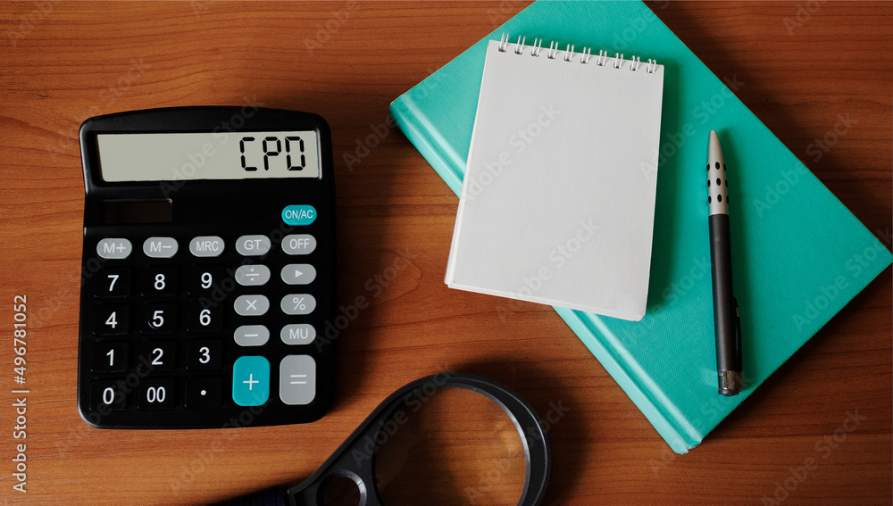 Calculator with CPD text on wooden background with notepad to write Calculator with CPD text on wooden background with notepad to write