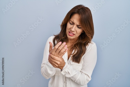 Фотография Hispanic woman standing over isolated background suffering pain on hands and fin