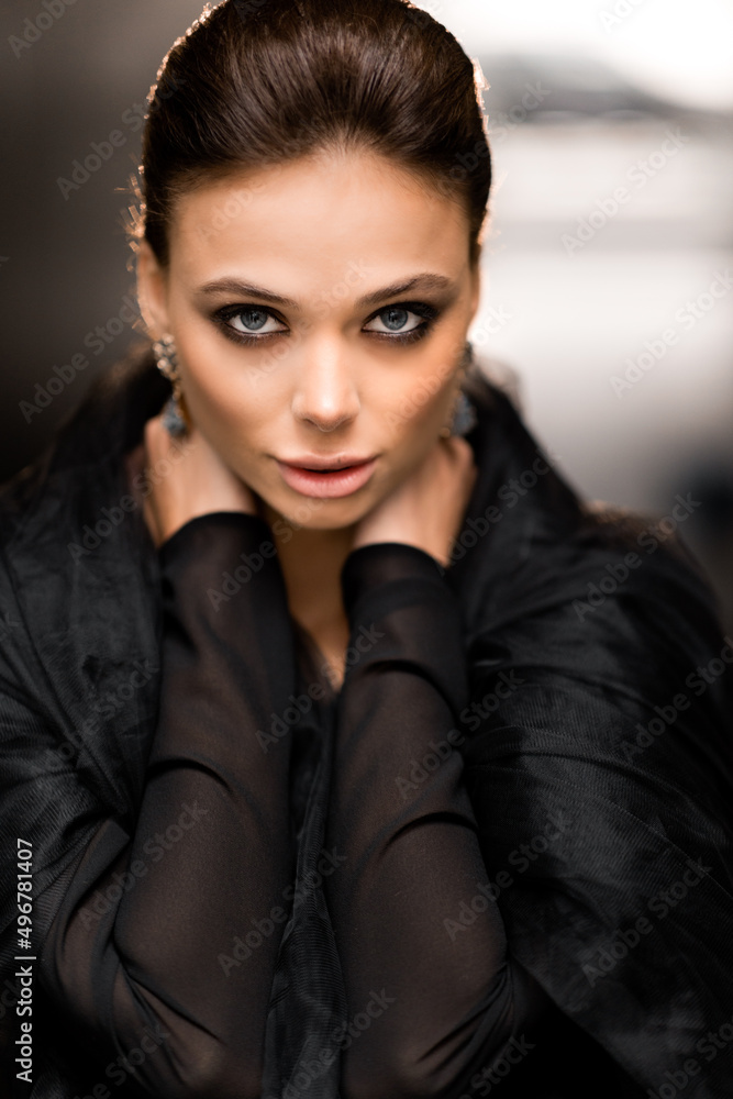 Portrait of stylish beautiful woman in black veil looking directly at the camera, posing for photo. Gorgeous female is working as a model on photoshoot for fashion magazine cover