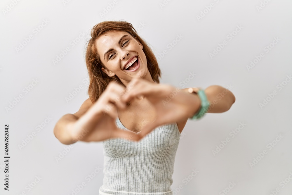 Beautiful caucasian woman standing over isolated background smiling in love doing heart symbol shape with hands. romantic concept.