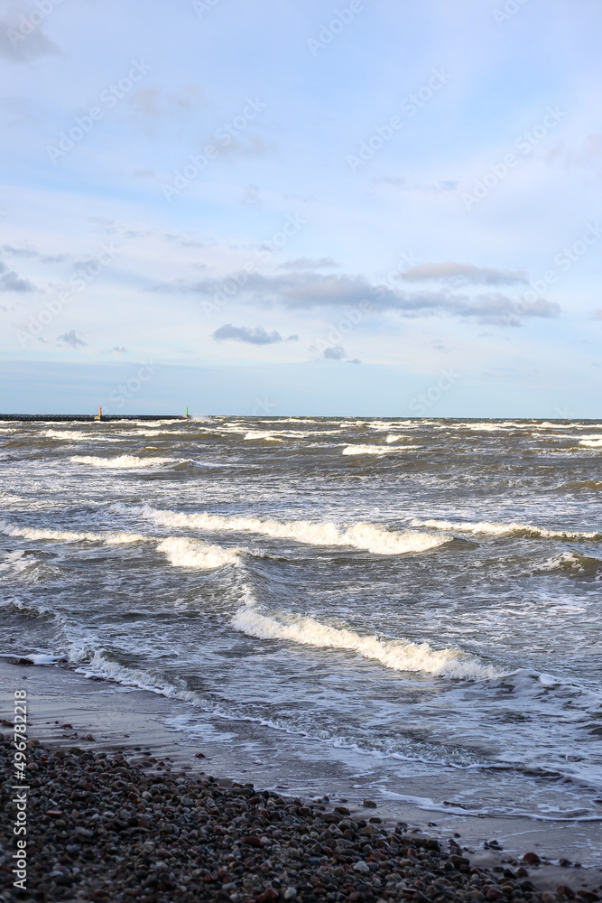 Baltic sea shoreside view with waves and cloudy weather.