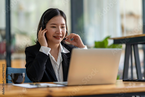 Happy Asian woman sitting in the office and video conference with a business partner on a laptop. Concept of a new lifestyle and social distancing