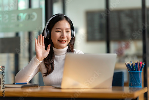 study abroad Asian girl wearing headphones watching laptop while doing homework video calling abroad using friend internet connection business women use computers to analyze financial data