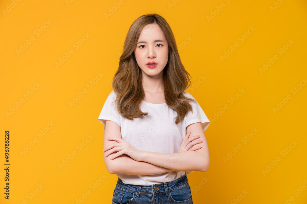 Face of angry young Asian girl standing and crossed arms on orange background. Face of angry young Asian girl standing and crossed arms on orange background.