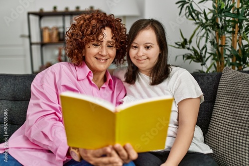 Mature mother and down syndrome daughter at home reading a book