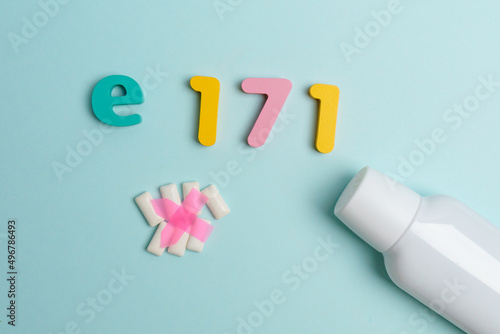 Chewing gum with e171 dangerous additive sign on blue background. Flat lay photo