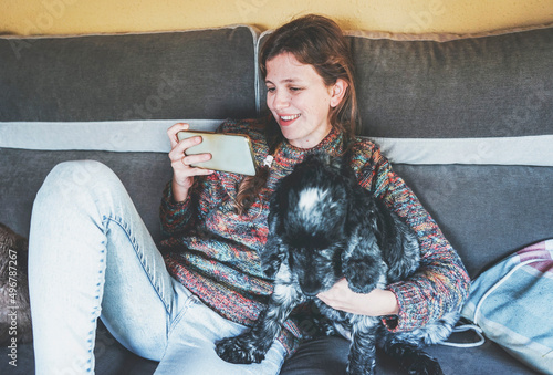 YOung woman using her smart phone white stand with her dog