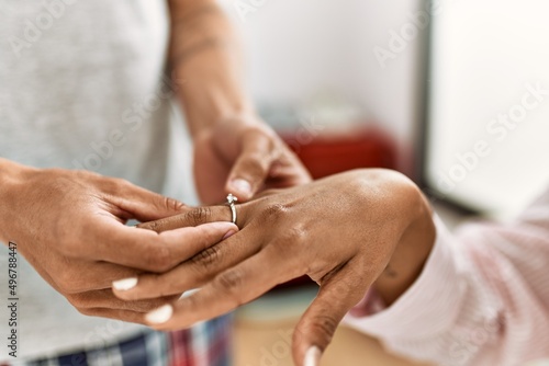 Hands of ouple on marriage proposal at the bedroom. Man putting engagement ring on woman finger.