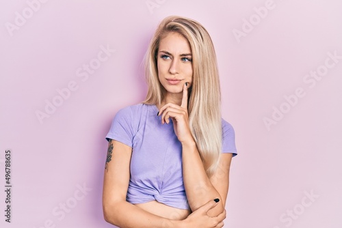 Young beautiful caucasian woman wearing casual t shirt serious face thinking about question with hand on chin, thoughtful about confusing idea