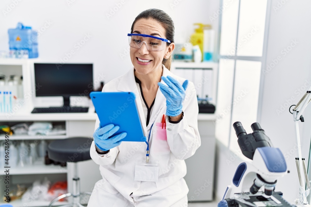 Young hispanic woman wearing scientist uniform having video call at laboratory