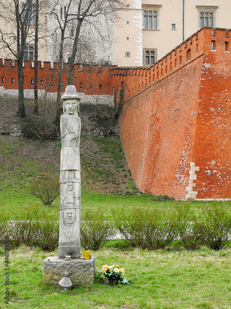 Zbruch Idol Sviatovid monument, copy of ancient sculpture of Slavic beliefs on background of brick defensive walls of Wawel Castle