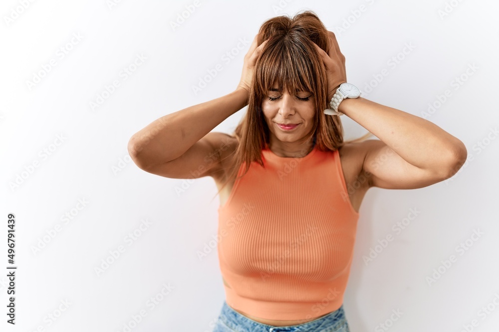 Hispanic woman with bang hairstyle standing over isolated background suffering from headache desperate and stressed because pain and migraine. hands on head. Hispanic woman with bang hairstyle standing over isolated background suffering from headache desperate and stressed because pain and migraine. hands on head.