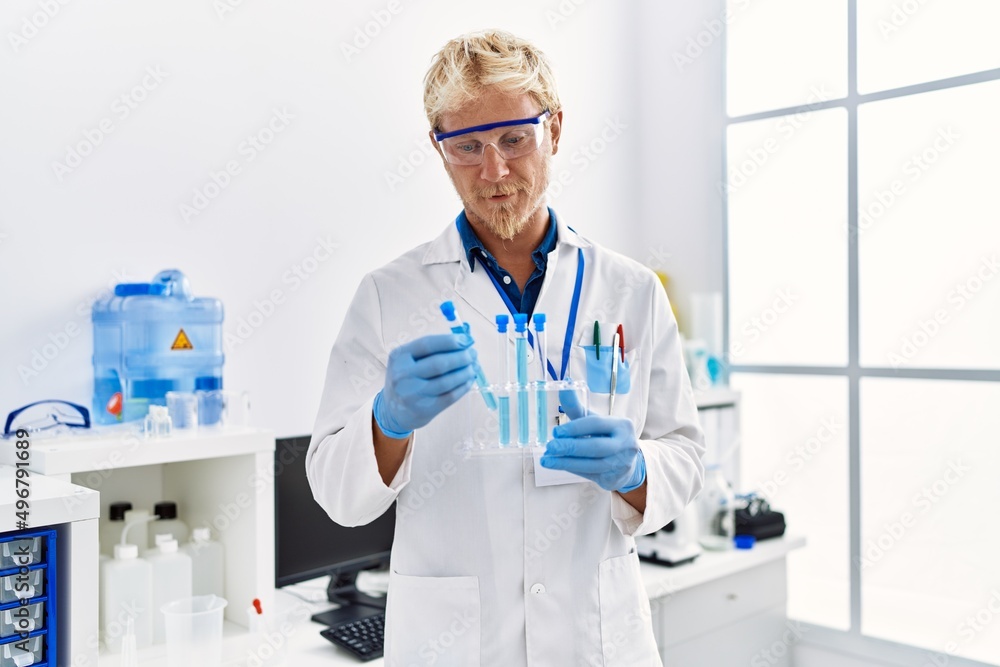 Young caucasian man wearing scientist uniform holding test tube at laboratory Young caucasian man wearing scientist uniform holding test tube at laboratory