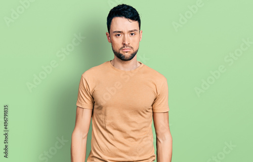 Hispanic man with beard wearing casual t shirt looking sleepy and tired, exhausted for fatigue and hangover, lazy eyes in the morning.