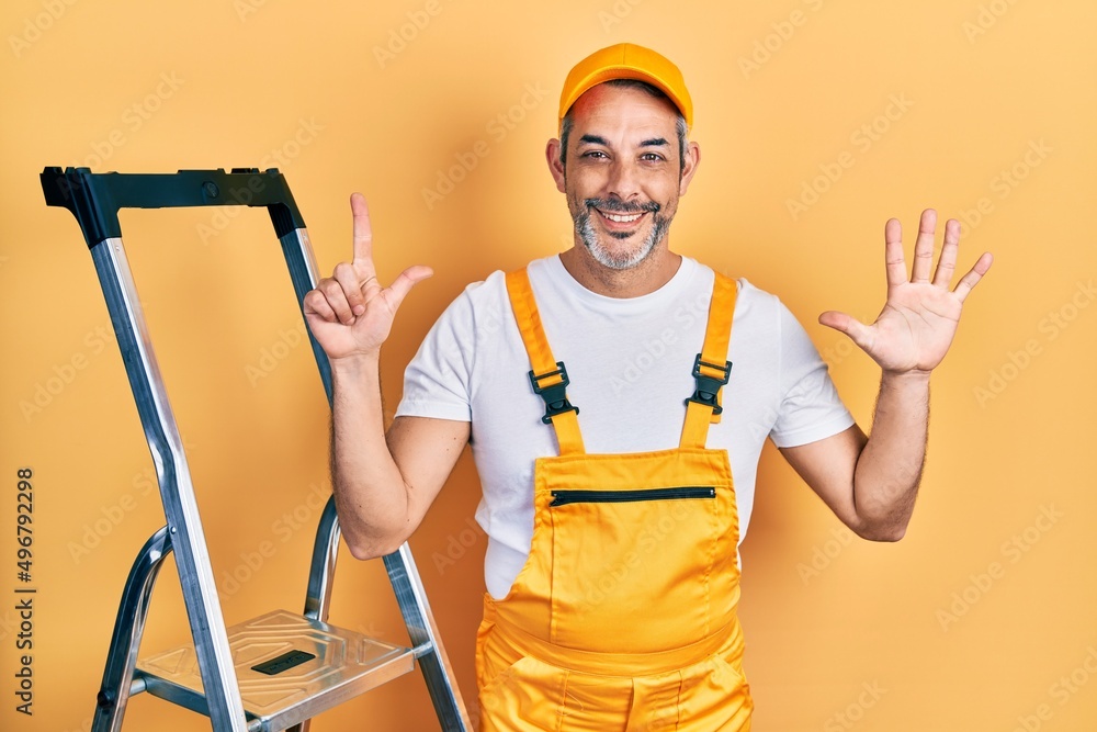 Handsome middle age man with grey hair holding ladder showing and pointing up with fingers number seven while smiling confident and happy. Handsome middle age man with grey hair holding ladder showing and pointing up with fingers number seven while smiling confident and happy.