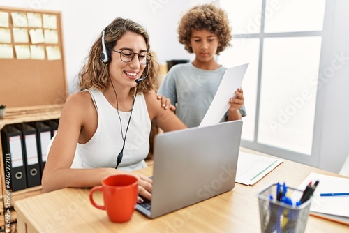 Young business mother working at the office with kid looking positive and happy standing and smiling with a confident smile showing teeth