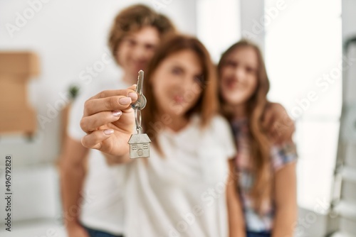 Mother and couple smiling confident holding holding key of new house at home