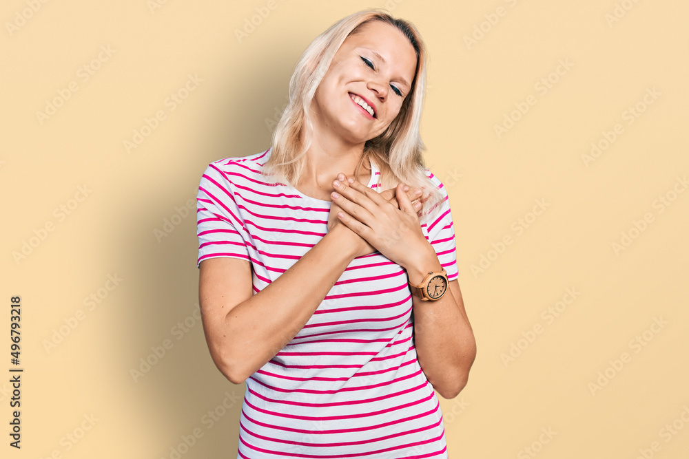 Young caucasian woman wearing casual clothes smiling with hands on chest with closed eyes and grateful gesture on face. health concept. Young caucasian woman wearing casual clothes smiling with hands on chest with closed eyes and grateful gesture on face. health concept.