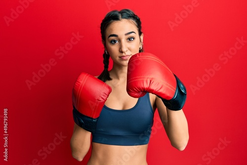 Young brunette girl using boxing gloves relaxed with serious expression on face. simple and natural looking at the camera. © Krakenimages.com