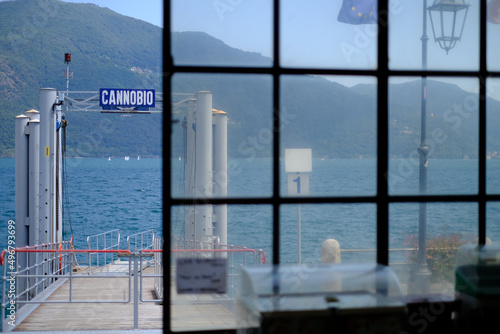 Photos Beautiful shot of a glass door on a ship with a Cannobio sign with green mountai